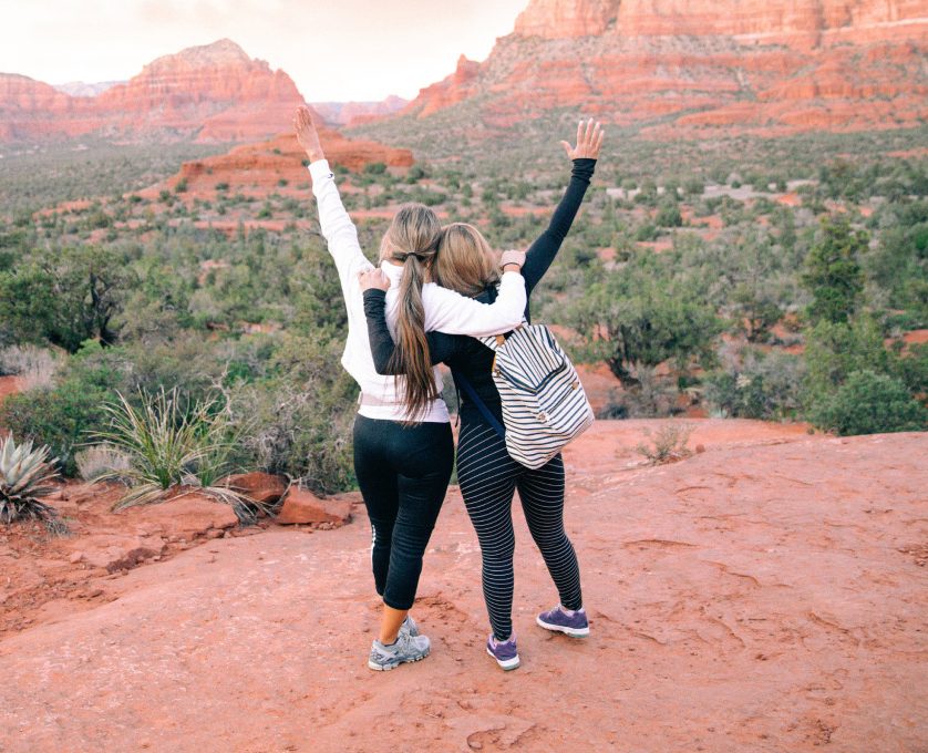 two woman at the top of a canyon with arms in the air